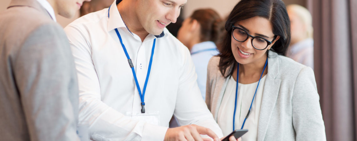 Tre personer på konferanse som ser på en telefon sammen