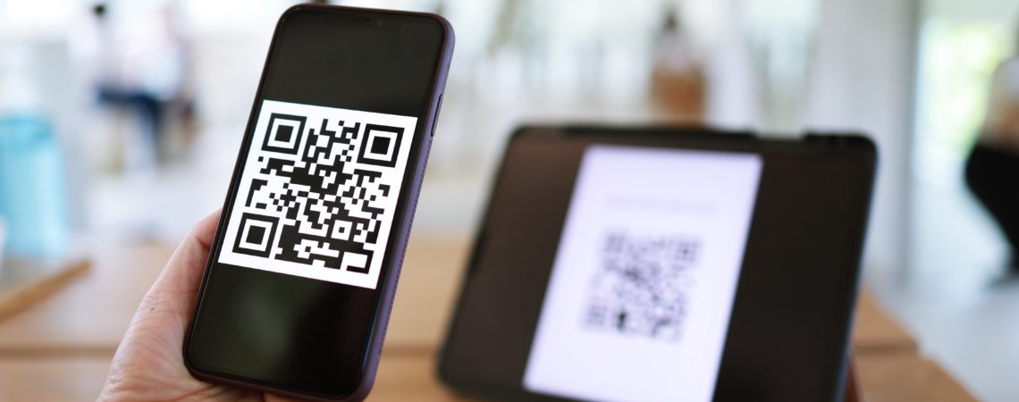 En mobil med en QR-kode holdes opp foran en skjerm med QR-kode for registrering.
