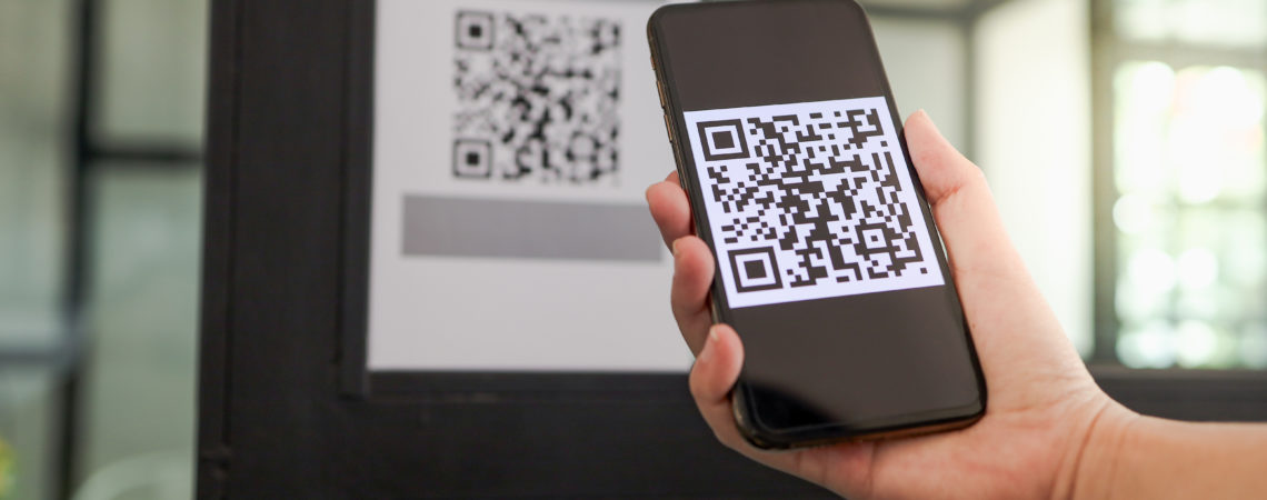 En person bruker en mobiltelefon for å scanne en QR-kode ved innsjekk