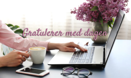 Utsnitt av kvinne ved skrivepult med hånden på laptop og kaffekopp