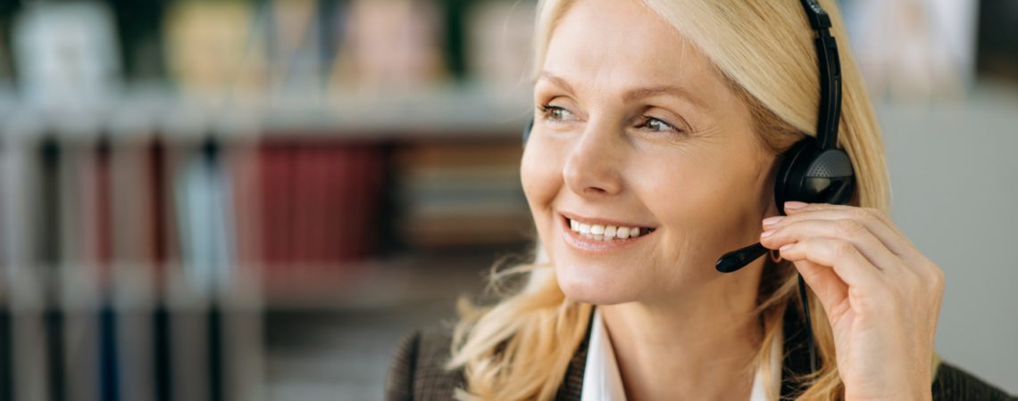 Nærbilde av blond smilende dame med headset