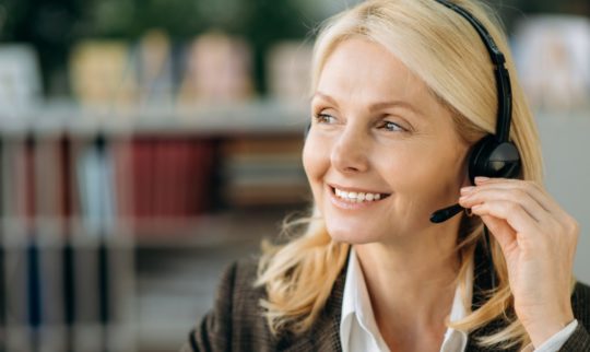 Nærbilde av blond smilende dame med headset