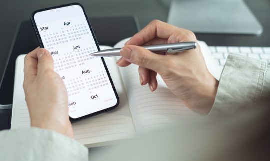 Holder en mobil mens hen velger dato i kalenderen