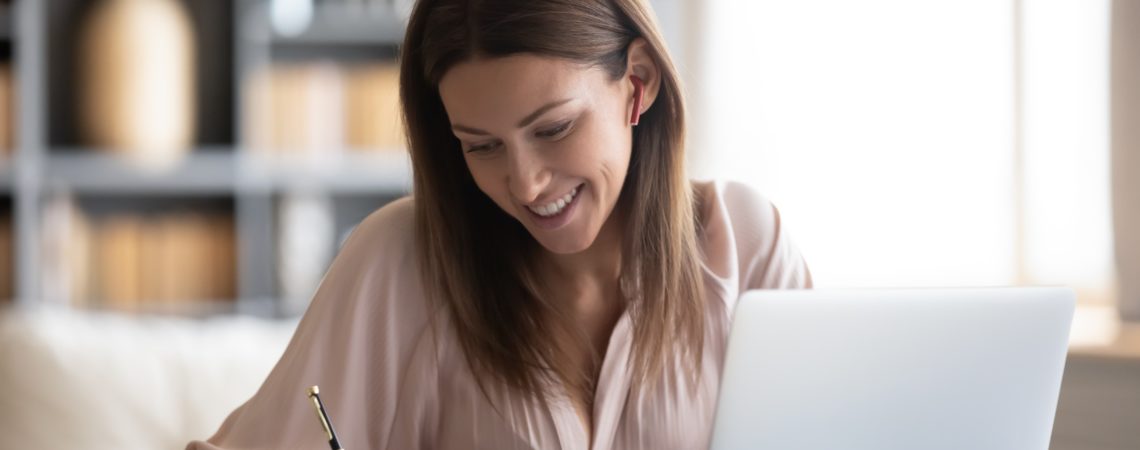 Dame ved kontorpult med laptop som sjekker en liste
