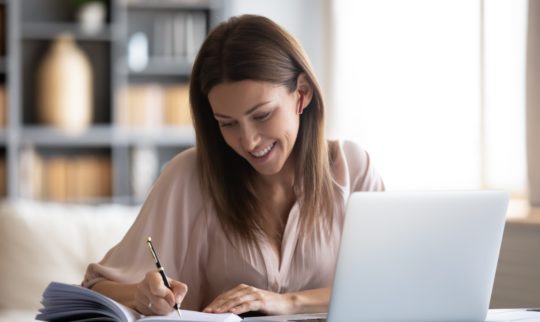 Dame ved kontorpult med laptop som sjekker en liste