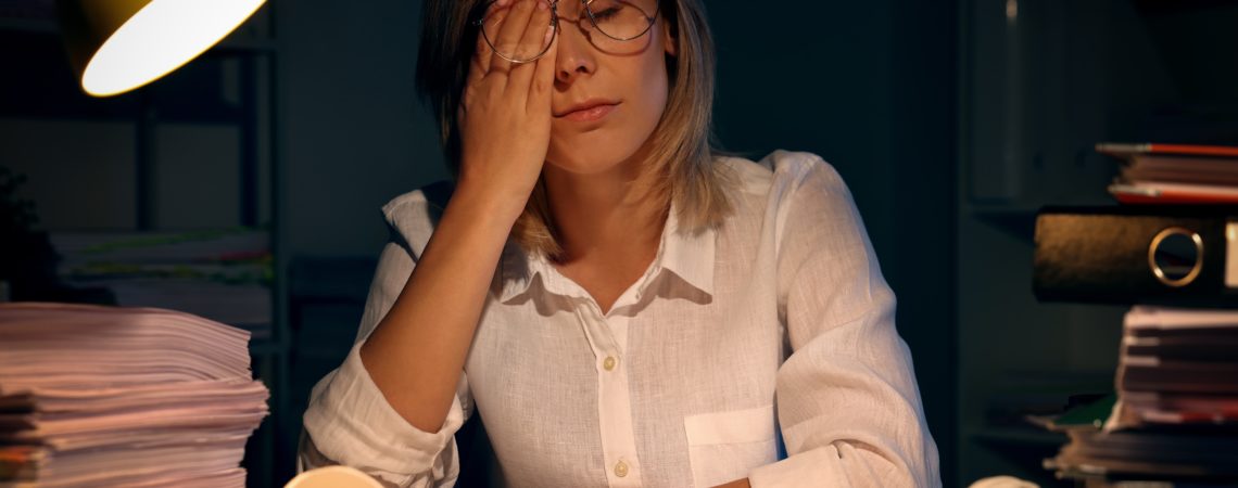 En dame overveldet av arbeid sitter ved en kontorpult