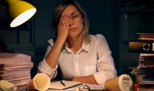En dame overveldet av arbeid sitter ved en kontorpult