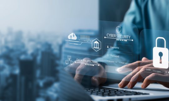 En hånd på laptop med illustrasjon foran som viser datasikkerhet