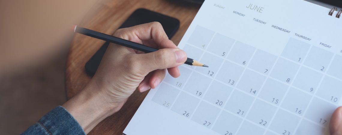 Utsnitt av en mann som skriver på en kalender